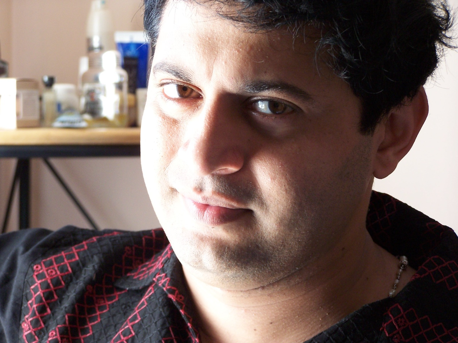 Close portrait of Deepak Thimaya in a black shirt with red embroidery